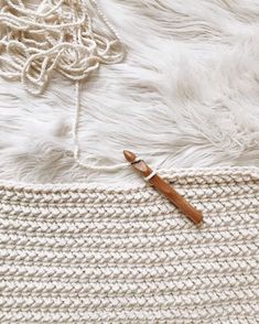 a crochet bag with a wooden handle on top of white sheepskin rug