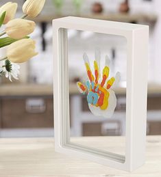 a vase filled with flowers sitting on top of a table next to a white frame