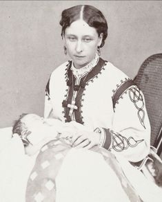 an old black and white photo of a woman holding a baby in her lap,