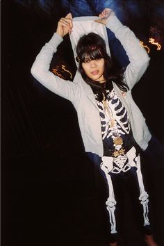 a woman in skeleton costume holding up her jacket over her head and posing for the camera