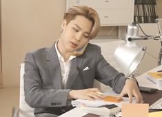 a man sitting at a desk in front of a computer and talking on the phone