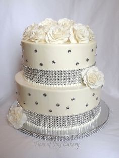 a three tiered wedding cake with white roses and diaper beading on top