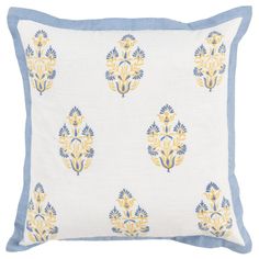 a white pillow with blue and yellow designs on it, sitting on a white surface