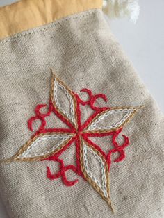 a red and white cross stitched on top of a piece of cloth