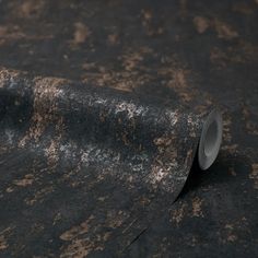 a roll of black and brown paper on top of a surface with rusted paint