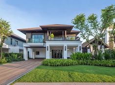 a large white house surrounded by lush green grass and trees with lots of windows on the second floor