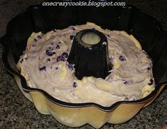 a cake pan filled with frosting and blueberries sitting on top of a counter