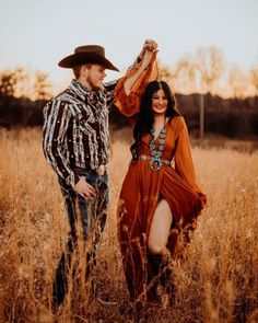 a man and woman standing in tall grass