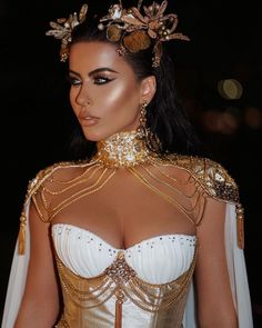 a woman in a gold and white dress with her hair styled into a headpiece