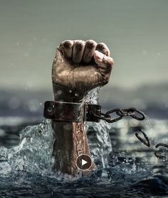 a hand holding a chain in the middle of water with another hand on it's side