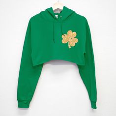 "\"GLITTER POCKET SHAMROCK\" St. Patrick's Day Cropped Hoodie for women Whether you are grabbing one of these for just yourself or a group of your best drinking buddies, you are sure to turn some heads! Crop Hoodie Women's Sizes: S, M, L, XL The crop length on this item is more on the shorter side vs long Shirt Colors: Black, Green, White Cotton/Poly Blend Perfect for: St. Patty's Day Brunch, Pub Crawls, Night Out, Casual Work Wear leading up to St. Patrick's Day, or St. Paddy's Day Parade" Trendy Green Crop Top For Fall, Trendy Hooded Winter Crop Top, Trendy Hooded Crop Top For Winter, Trendy Hoodie Crop Top For Fall, Trendy Fall Crop Top Hoodie, Crop Hoodies, Casual Work Wear, Drinking Buddies, St. Patricks Day