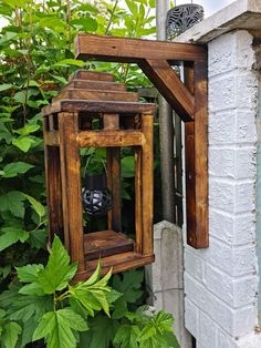 a wooden lantern hanging from the side of a white brick building surrounded by greenery