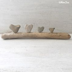 four hearts are arranged on a piece of driftwood and placed on top of each other