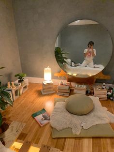 a woman taking a selfie in front of a mirror on the floor with books and candles