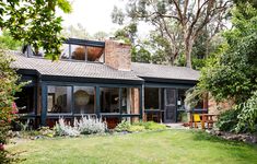 a house that is surrounded by trees and grass with lots of windows on the roof