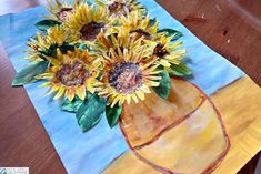 sunflowers are in a vase on a blue and yellow table cloth with watercolor paper