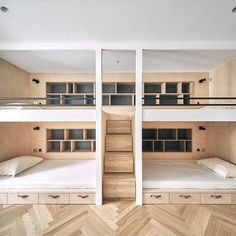 two bunk beds in the middle of a room with wooden flooring and white walls