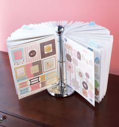 an open book sitting on top of a wooden table next to a file folder and binder