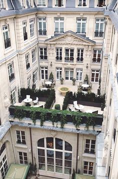 an aerial view of a building with tables and chairs in the courtyard, looking down