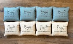 six blue and white pillows with the names of different brands on them sitting on a wooden surface