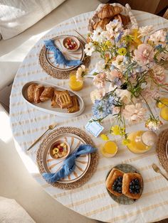 the table is set with flowers, fruit and pastries for breakfast or brunch