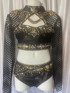 a mannequin wearing a black top with gold sequins and chains on it