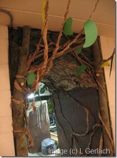 a mirror that has some branches hanging from it's sides and is decorated with leaves