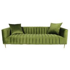 a green velvet sofa with two pillows on the back and one pillow on the side