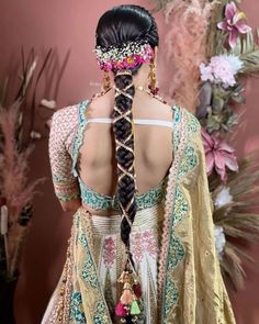 the back of a woman's head with braids and flowers in her hair