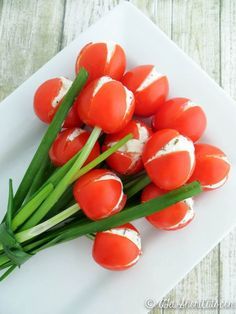 there are many tomatoes on the plate with green onions around them and some white cheese