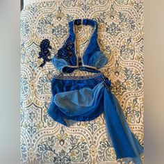 a blue dress laying on top of a bed next to a white and blue wall