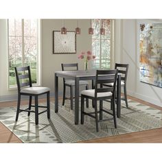 a dining room table with four chairs and a rug