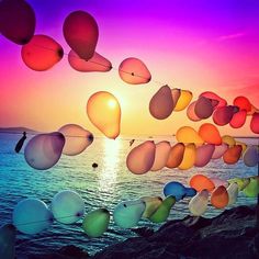 many balloons floating in the air over water