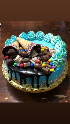 a cake with ice cream, chocolate and candy on it sitting on top of a wooden table