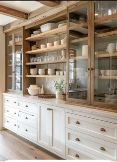 a kitchen with lots of white dishes on the shelves and cupboards in front of it