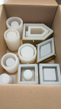 there are many different white objects in the box, including cups and saucers on the table