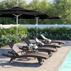 several lounge chairs and an umbrella near a swimming pool