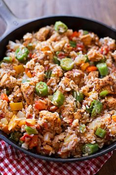 a skillet filled with rice and vegetables on top of a checkered table cloth