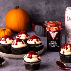 cupcakes with white frosting and red sauce next to a bag of jam