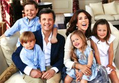 a family sitting on a couch in front of a white sofa with two children and one adult