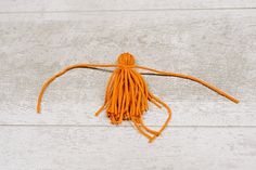 an orange tasseled object on a white wooden surface