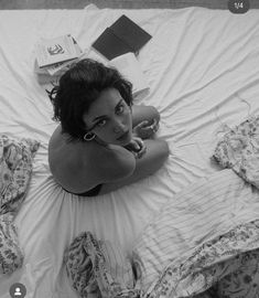 a woman laying on top of a bed next to a book