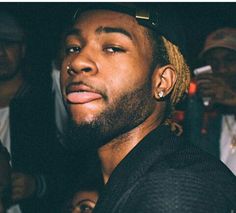 a close up of a person in a crowd with other people behind him and one man looking at the camera