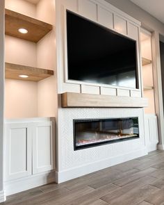 an empty living room with a large flat screen tv mounted above the fireplace and built - in shelving