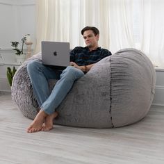 a man sitting on a bean bag chair using his laptop