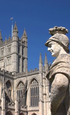 a statue in front of a castle with a clock on it's face and an ornate tower