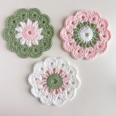 three crocheted flower coasters sitting on top of a table