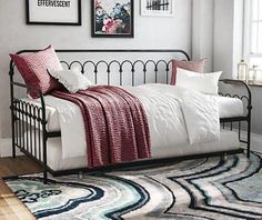 a bedroom with a bed, rug and pictures hanging on the wall above it's headboard