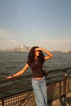 a woman standing next to the water with her hands on her head