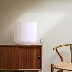 a wooden chair sitting next to a white lamp on top of a dresser in a room